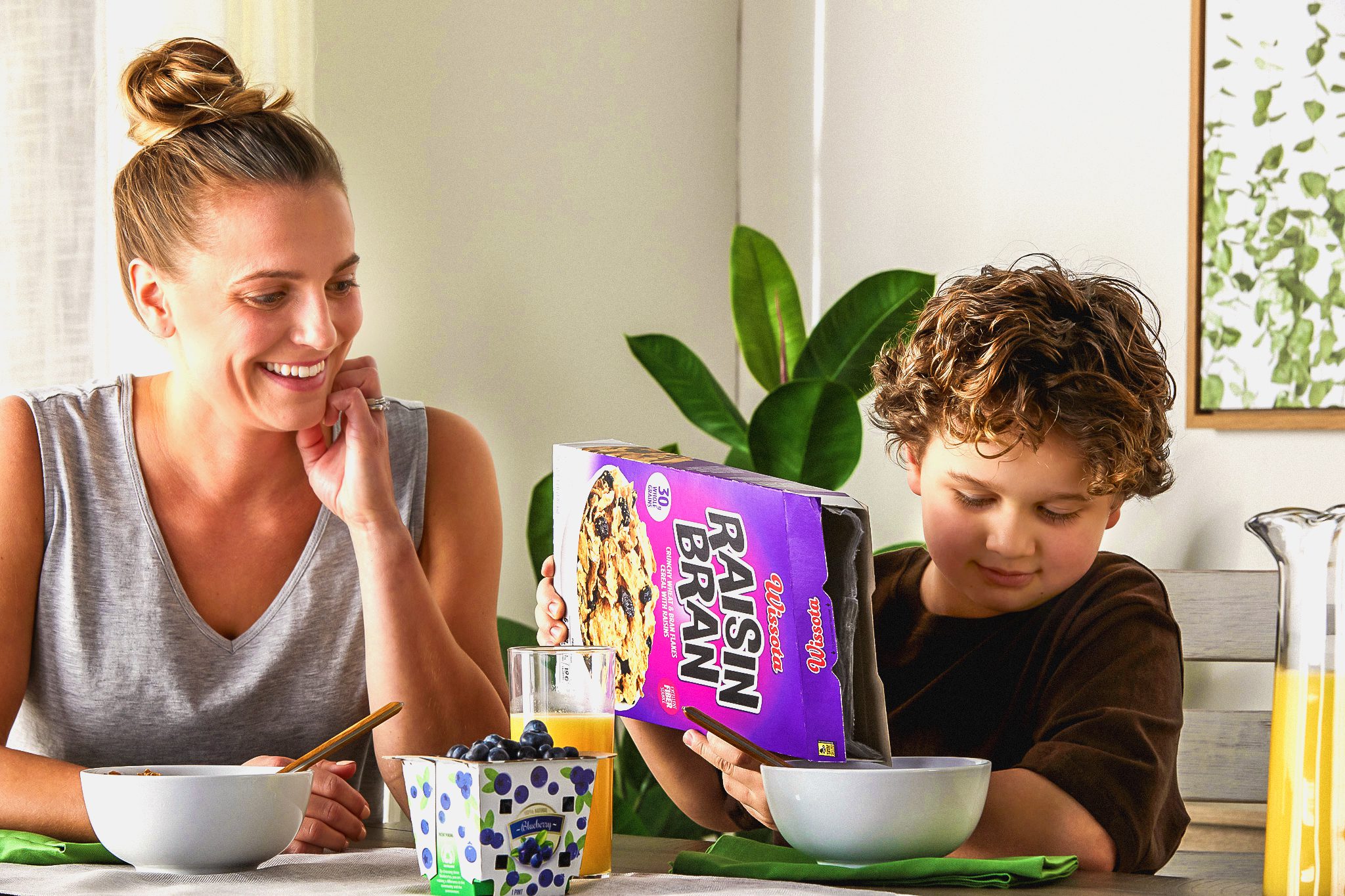 Mother watching child pour a cereal carton into bowl