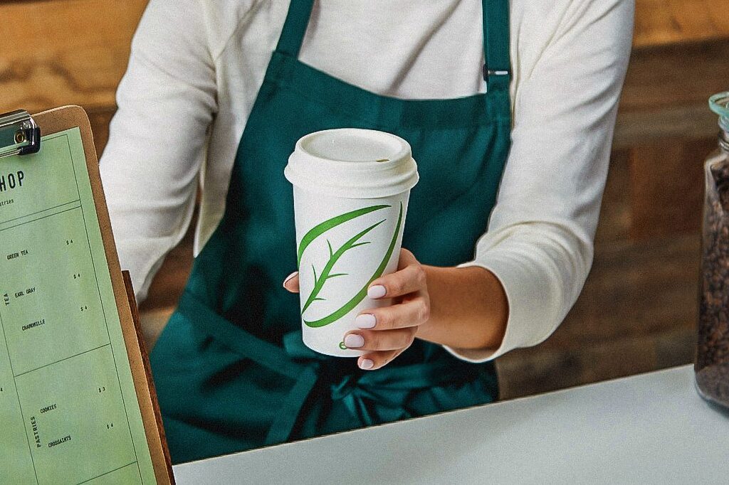 A barista handing coffee to someone using Graphic Packaging's ecotainer hot cup