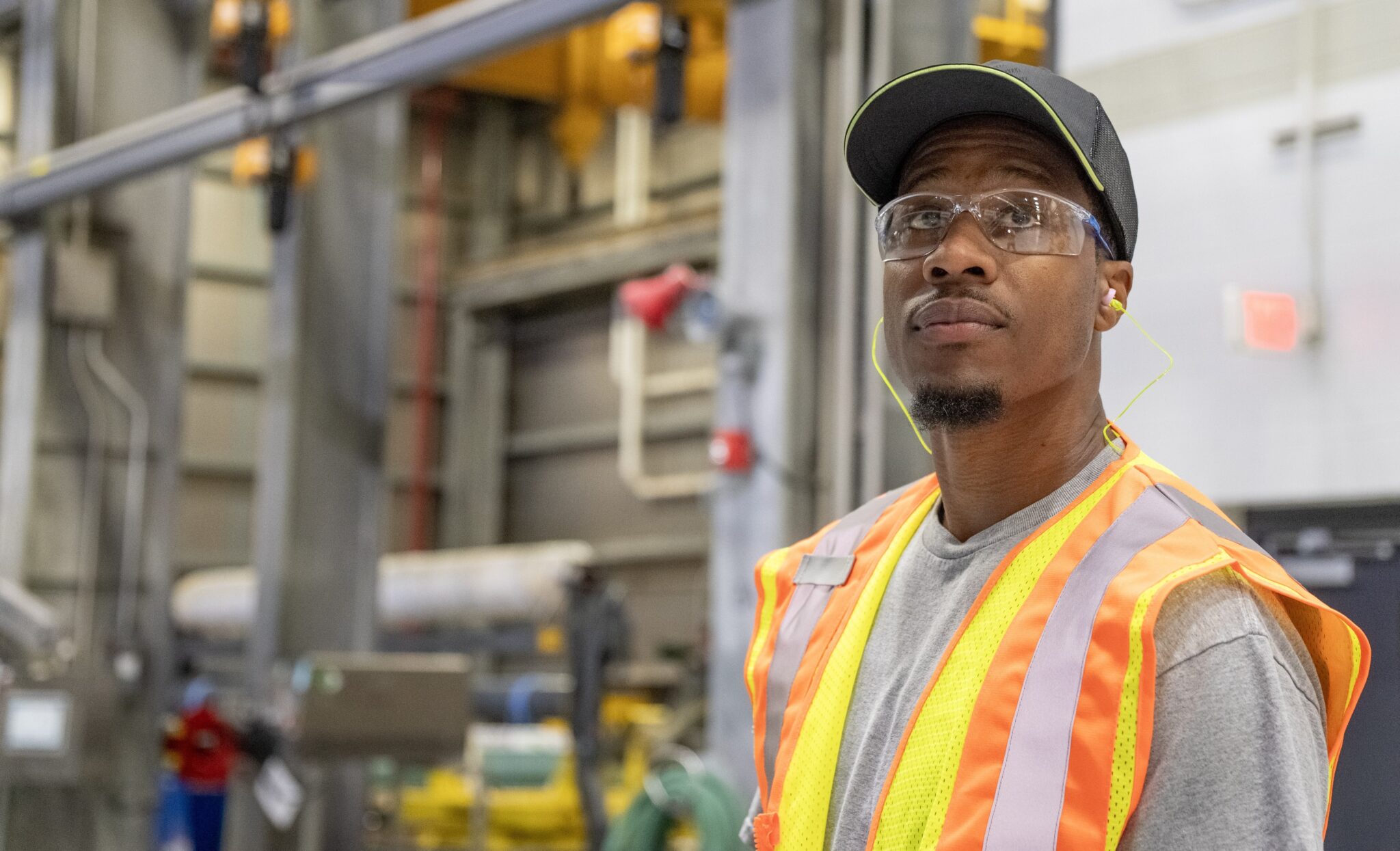 Man in safety vest and goggles inside Graphic Packaging manufacturing facility