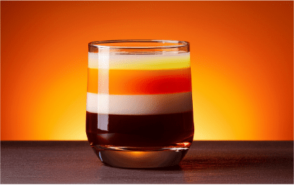 distinctive striped layer fusion drink in a clear glass against a warm background