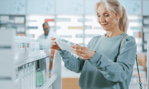 Beautiful Senior Woman Walking Between aisles and Shelves with Medicine, Choosing to Buy Medicine